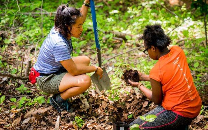 two young people use gardening tools during a service day with outward bound